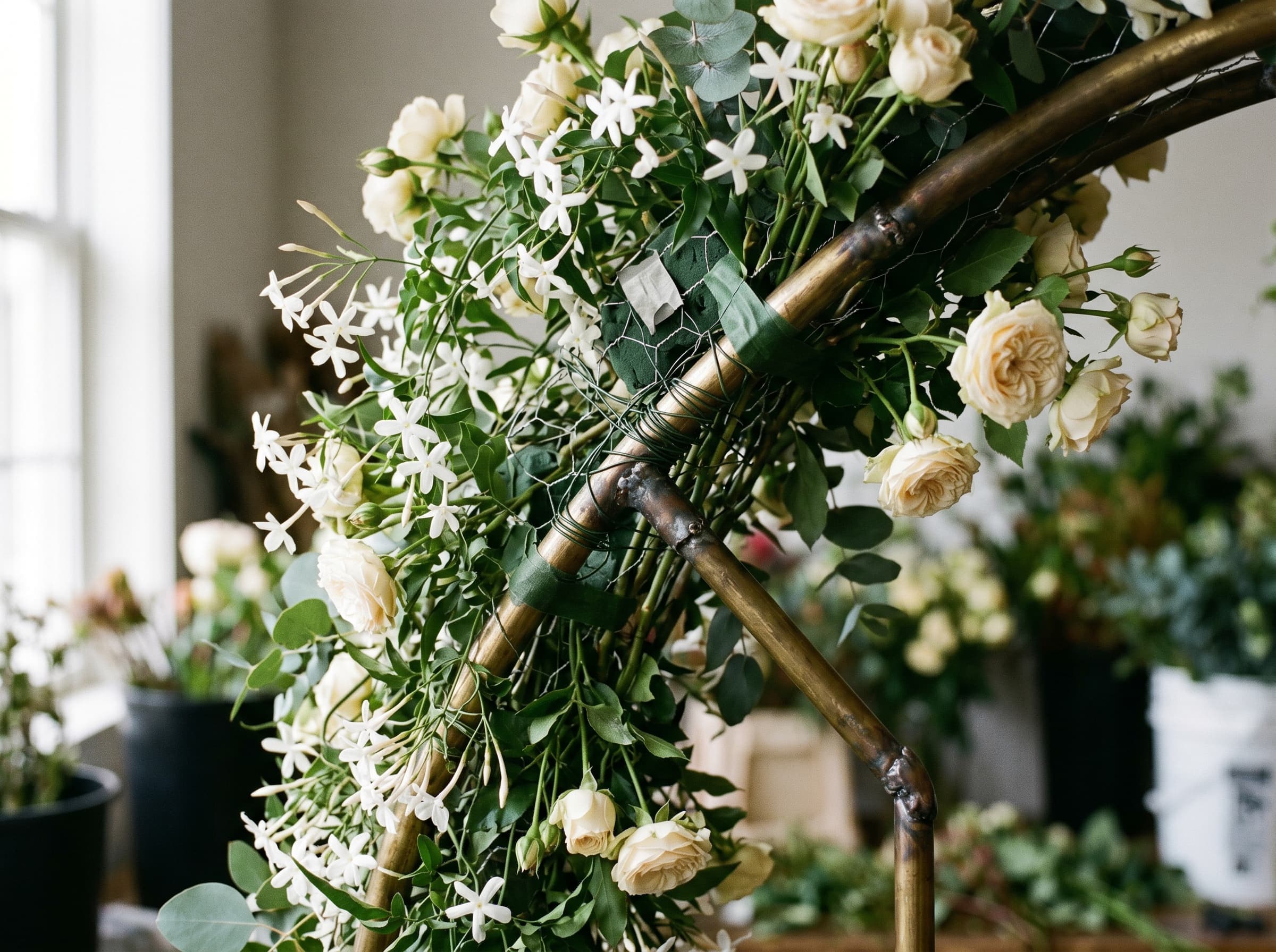 Close-up detail of floral installation brass armature with jasmine and cream spray roses